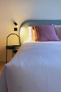 Oporto CoLiving Monte Ramalde في بورتو: سرير أبيض مع وسادة أرجوانية وطاولة جانبية