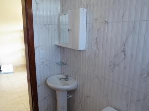 La salle de bains blanche est pourvue d'un lavabo et d'un miroir. dans l'établissement APEVO ILHA, à Ilha Comprida