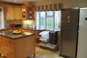 a kitchen with a refrigerator and a toilet in it at Hectors House comfortable 4 bed house in mature gardens in Yelverton