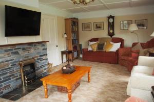 een woonkamer met een bank en een open haard bij Hectors House comfortable 4 bed house in mature gardens in Yelverton