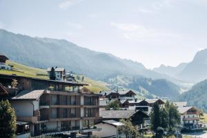 eine Gruppe von Gebäuden in einem Dorf mit Bergen im Hintergrund in der Unterkunft Hotel Plan Murin  in Wengen