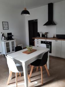 una cucina bianca con tavolo e sedie bianchi di Gîte des Agapanthes a Lacroix-sur-Meuse
