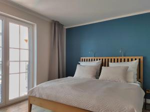 una camera da letto con pareti blu e un letto con cuscini bianchi di Jolle 54 a Putbus