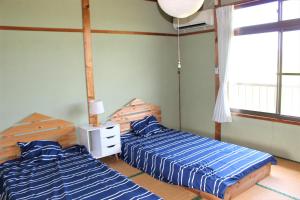 1 dormitorio con 2 camas y ventana en ikibase Guest House, en Iki