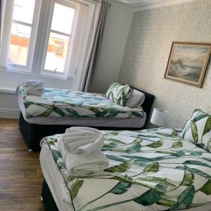 two beds in a hotel room with towels on them at Albert Road Apartment in Eyemouth