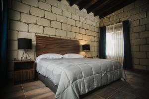 1 dormitorio con 1 cama grande y pared de ladrillo en Real de Corralejo, en San Miguel de Allende