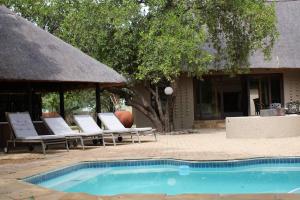 a swimming pool with lounge chairs and a building at 86 Zebula 12 Sleeper Lodge in Mabula
