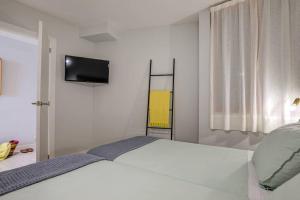 a white bedroom with a bed and a television at Auborada 1A in Port de Pollensa