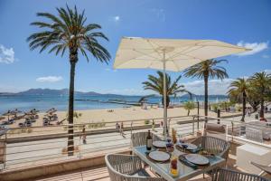 a table with chairs and an umbrella on the beach at Auborada 1A in Port de Pollensa
