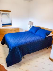 - une chambre avec un lit bleu et une couette bleue dans l'établissement Peck's Housekeeping Cottages, à Louisbourg