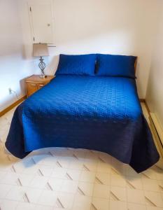 - un lit avec une couette bleue dans une chambre dans l'établissement Peck's Housekeeping Cottages, à Louisbourg