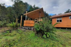 een houten blokhut met een groot vat in de tuin bij Pillang Likan tinas calientes, el poder del Volcan in Puerto Varas