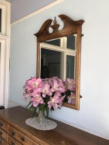 a vase of pink flowers on a dresser in front of a mirror at Dorstan House in Edinburgh