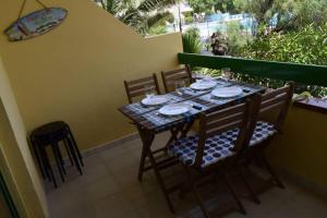 una mesa con sillas, platos y vasos en el balcón en Appartement Bouganville rez-de-chaussée WIFI, en Costa de Antigua