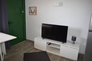 sala de estar con TV de pantalla plana en un centro de entretenimiento blanco en Appartement Bouganville rez-de-chaussée WIFI, en Costa de Antigua