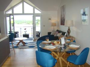 a living room with a glass table and blue chairs at Topsail, Falmouth in Falmouth
