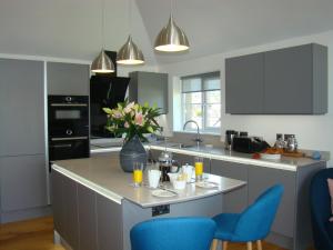 a kitchen with a island with blue chairs and a vase of flowers at Topsail, Falmouth in Falmouth