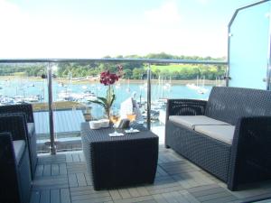 a balcony with chairs and a table with a view of a harbor at Topsail, Falmouth in Falmouth