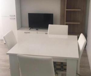 einen weißen Tisch mit weißen Stühlen und einen TV in der Unterkunft ESTUDIO VILA PRAIA DE ÂNCORA in Vila Praia de Âncora