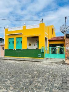 a yellow and green building with blue windows at Casa com Piscina in Canavieiras