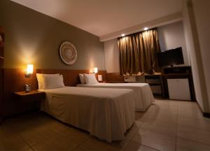 um quarto de hotel com duas camas e uma televisão em Executive Inn Hotel em Uberlândia