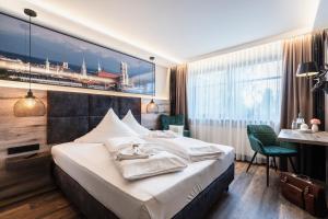 ein Hotelzimmer mit einem großen Bett und einem Schreibtisch in der Unterkunft Hotel Demas München-Unterhaching in Unterhaching