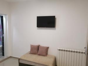 Cette chambre blanche dispose d'une chaise et d'une télévision murale. dans l'établissement Apartments Familia, à Budva