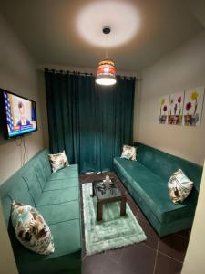 Porto Matrouh Chalet X Rent family only في مرسى مطروح: غرفة معيشة مع أريكة خضراء وطاولة