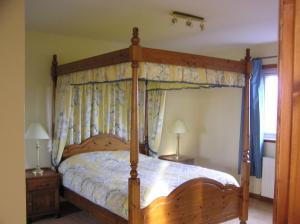 a bedroom with a wooden bed with a canopy at The Antlers in Lybster