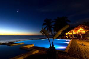 a swimming pool at night next to the beach at Anjiamarango Beach Resort in Nosy Be