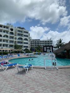 a resort swimming pool with chairs and people in the water at Ocean view Aquamarina in Cancún