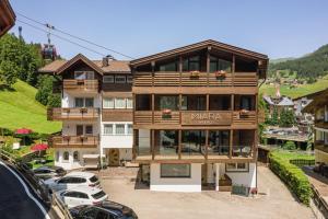 a large building with cars parked in a parking lot at Garni Hotel Miara - Your Dolomites Home in Selva di Val Gardena