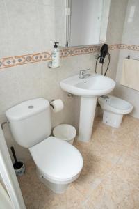 a white bathroom with a toilet and a sink at Teniente Ruiz 27 in Elche