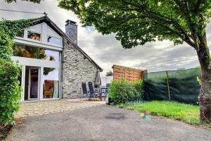 a stone house with a patio and a tree at Lî Gurni in Houffalize