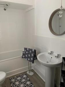 uma casa de banho branca com um lavatório e um espelho em Peveril Cottage em Castleton