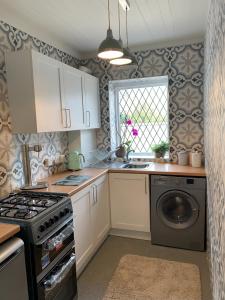 uma cozinha com um fogão, um lavatório e uma máquina de lavar louça em Peveril Cottage em Castleton