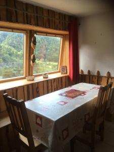 a dining room with a table and two windows at Appartement chalet Bellevue-pied de la montagne - Mont Dore in Le Mont-Dore