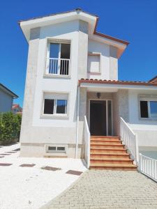 una casa blanca con escaleras delante en CHALET A SOLO 5 MIN DE OURENSE CIUDAD con jardín y barbacoa, en Ourense