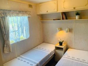 2 Betten in einem kleinen Zimmer mit Fenster in der Unterkunft Brīvdienu treileris in Mērsrags