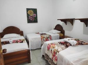 three beds in a room with white walls at Hotel Barajas in Jardin