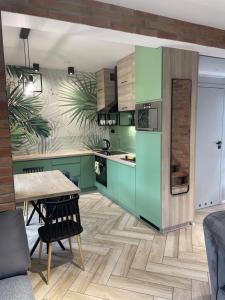 a kitchen with green cabinets and a wooden table at Zielone Rozewie Park in Rozewie