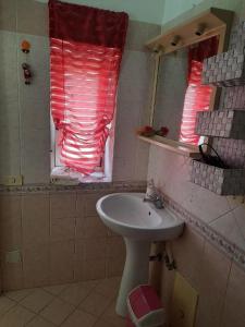un bagno con lavandino e una finestra con persiane rosse di La Sosta a Sant'Egidio del Monte Albino