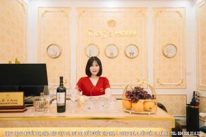 a woman sitting at a table with a bottle of wine at King's Hotel Nguyễn Thị Định in Hanoi