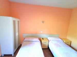 Duas camas num quarto com paredes cor de laranja em Casa de Huespedes La Asturiana em Madri