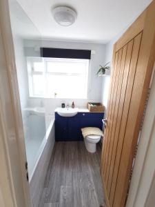 a bathroom with a tub and a sink and a toilet at Seaside bungalow 5 mins walk to beach and town in Bude