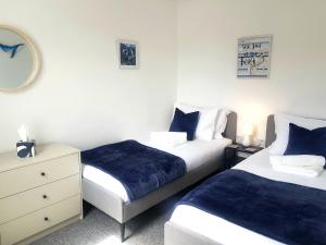 ein Schlafzimmer mit zwei Betten und einer Kommode in der Unterkunft Blue Horizon Holiday Cottage - 4 Minute Walk to the Beach in Weymouth