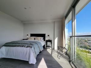 a white bedroom with a bed and a large window at Union Green Apt w Stunning Views - Free Parking in Auckland