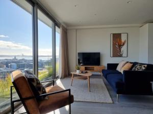 a living room with a blue couch and a large window at Union Green Apt w Stunning Views - Free Parking in Auckland
