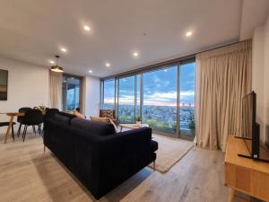 a living room with a black couch and a large window at Union Green Apt w Stunning Views - Free Parking in Auckland