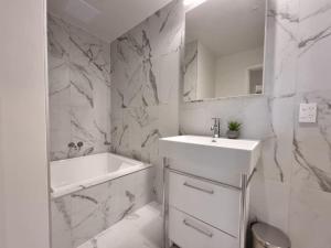 a white bathroom with a sink and a bath tub at Union Green Apt w Stunning Views - Free Parking in Auckland +67 photos